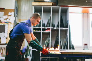 Glazier Worker Cutting Glass With Fire In A Workshop - Glass Assessoria Contábil